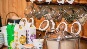 Un buffet pour le petit-déjeuner proposant divers aliments et boissons, notamment des pots d’épices, des briques de lait et une cafetière.