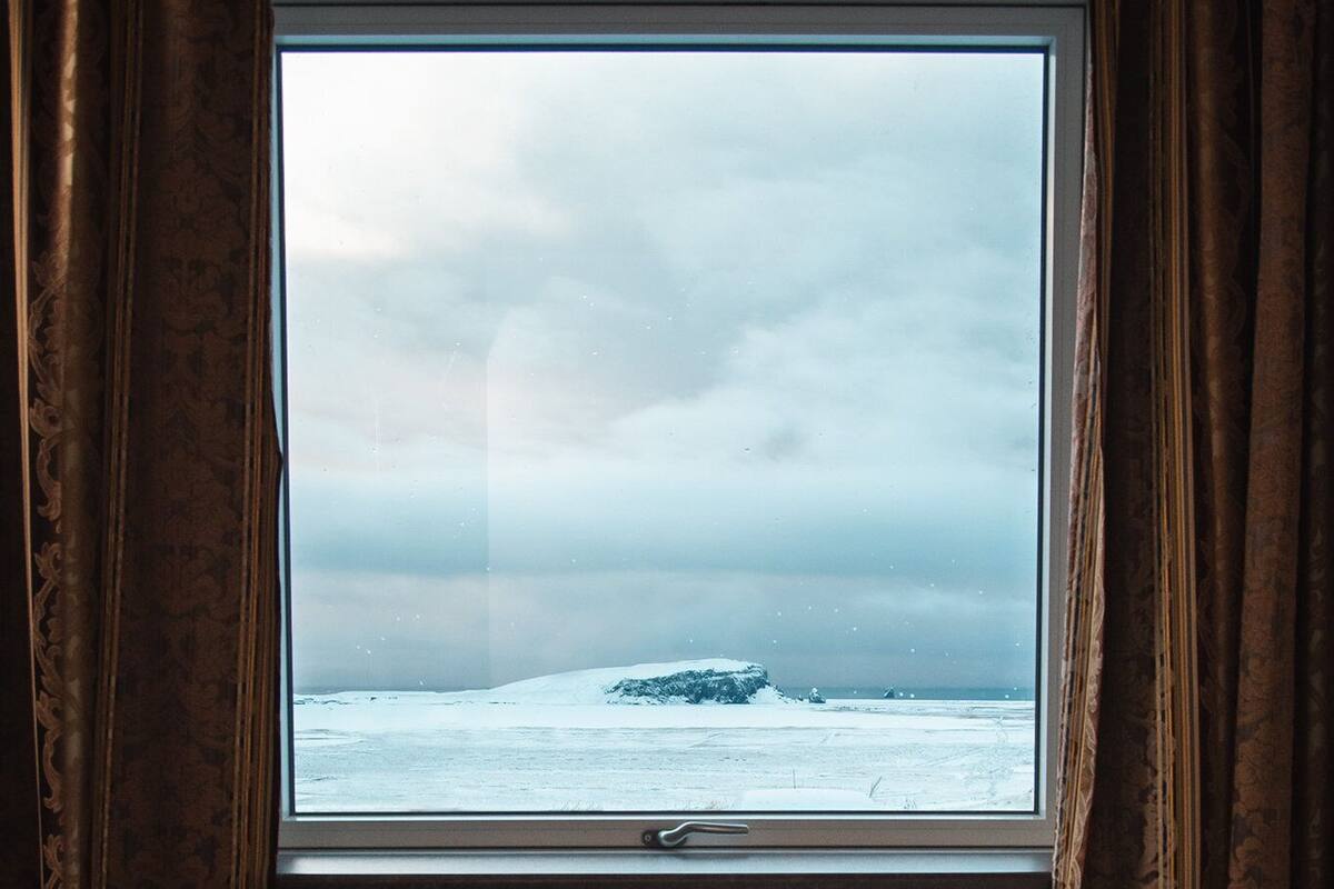 A room with a large window overlooking a snowy landscape.