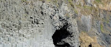 A large, rugged cliff with a cave entrance.