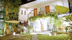 A modern house with a covered patio, outdoor seating, and a staircase leading to an upper level. - W Home Cipete (Jakarta)