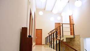 A modern staircase with wooden railings and a stone wall. - W Home Cipete (Jakarta)