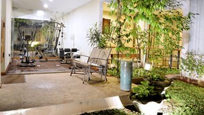 A gym with exercise equipment, a bench, and potted plants. - W Home Cipete (Jakarta)