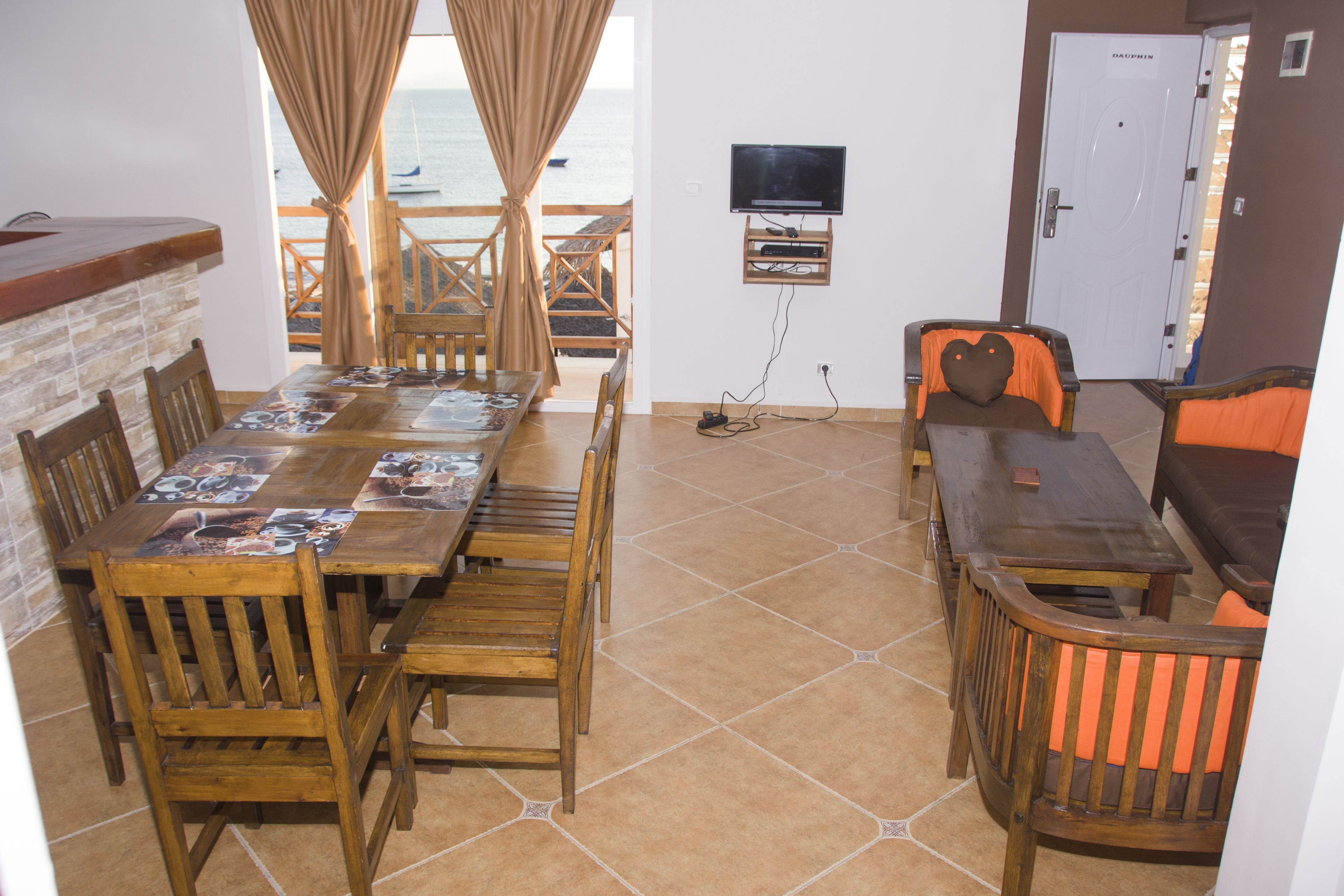 A dining area with a long wooden table, chairs, and a television mounted on the wall.