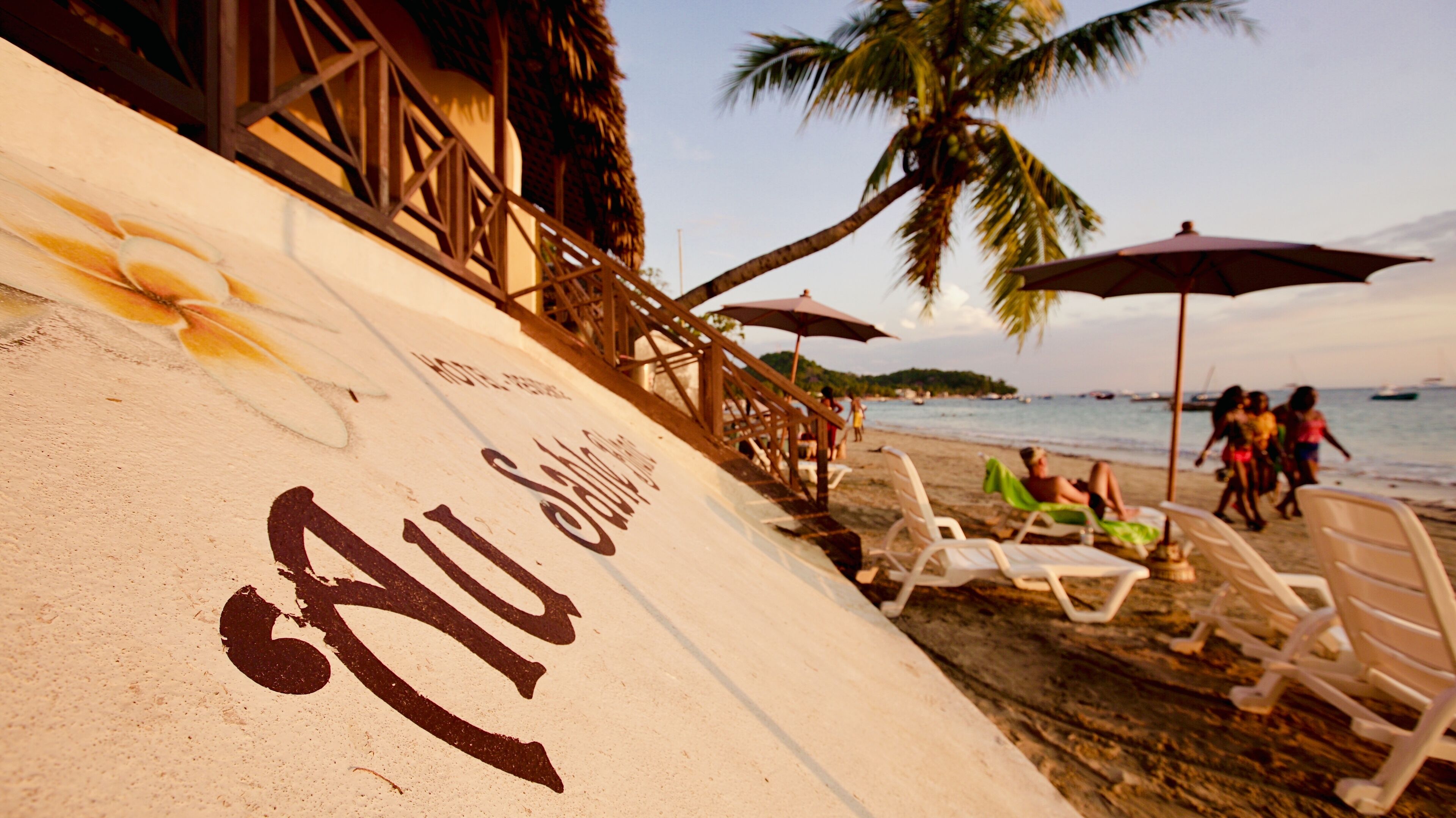 A beach with white sand, a wooden structure, and a palm tree.