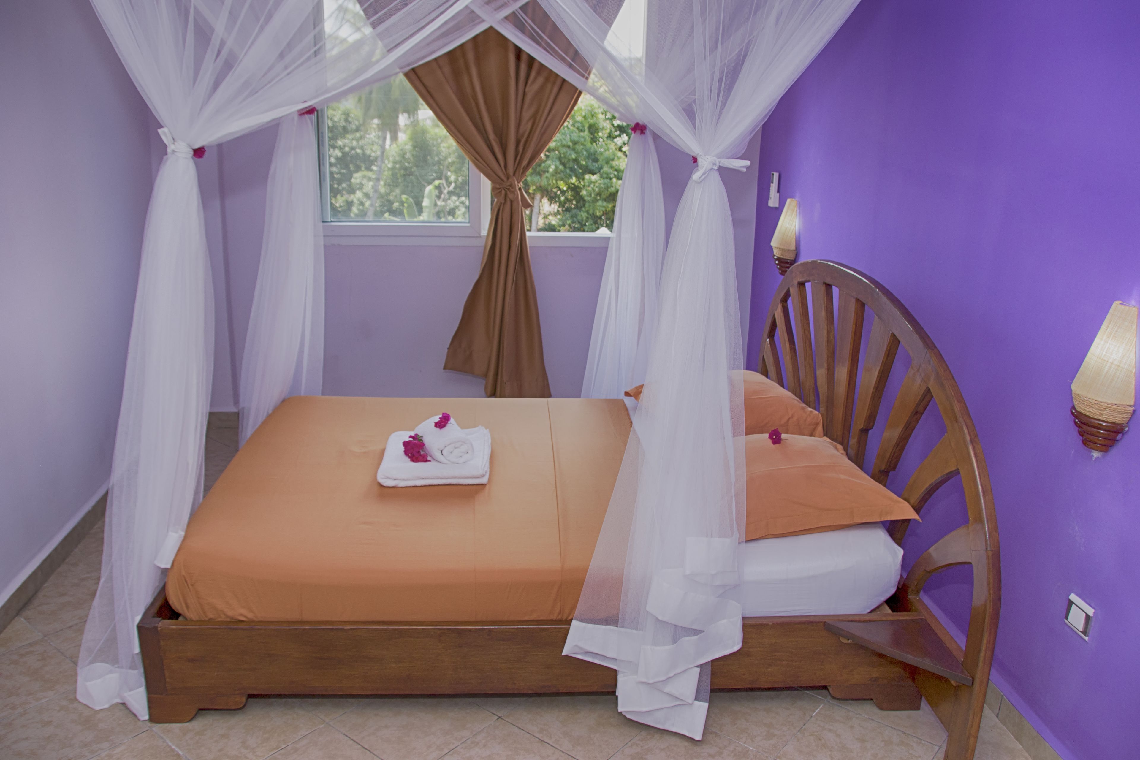 A bed with a wooden frame, white and brown bedding, and a canopy.