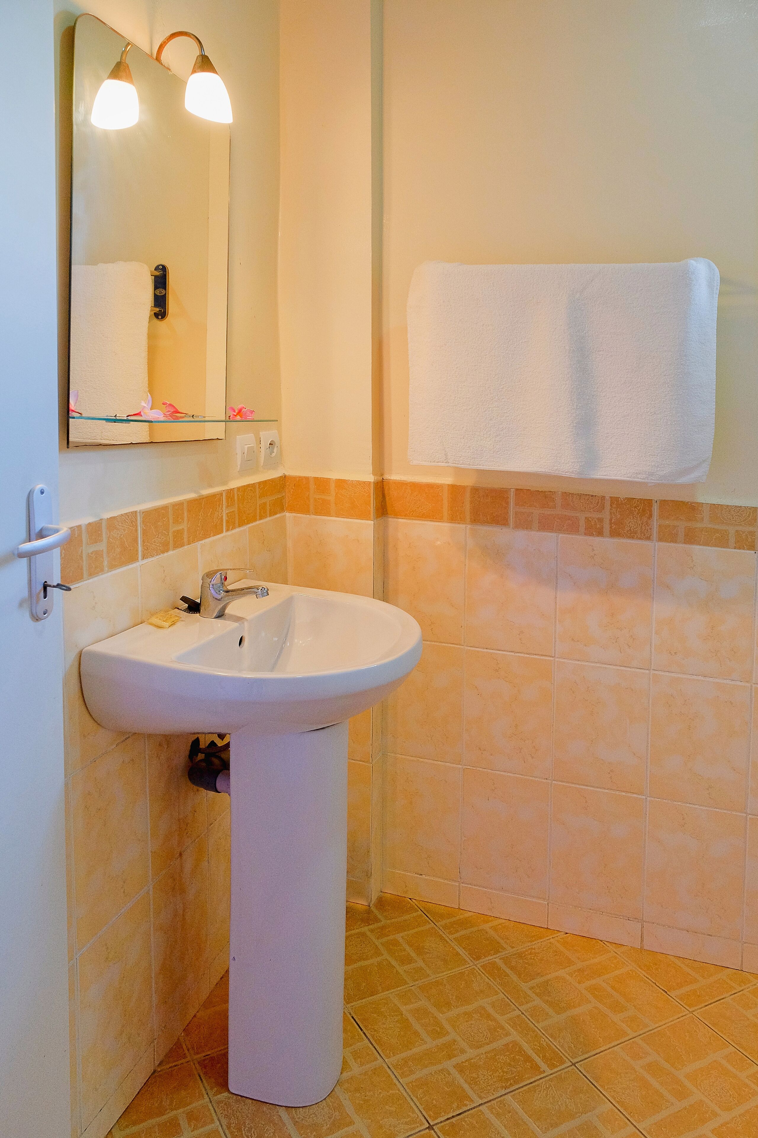 A bathroom with a white sink, a mirror, and a towel hanging on the wall.