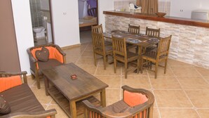 Un coin repas avec une table et des chaises en bois, un comptoir de cuisine et une salle de bain visible à travers une porte ouverte.