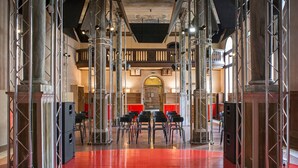 A spacious hall with a red floor, multiple black chairs arranged in rows, and a central archway. - Combo Venezia (Venice)