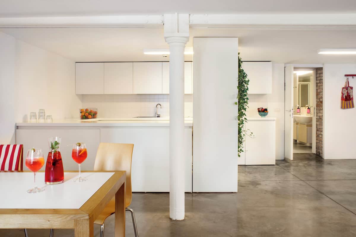 A modern kitchen with white cabinets, a central island, and a dining area with a table and chairs.