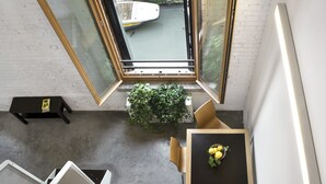 Ein Zimmer mit Tisch, Stühlen, einer Topfpflanze und einem Fenster mit Blick auf ein Boot.