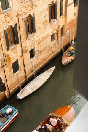 Un canal con barcos amarrados a lo largo de un edificio de ventanas arqueadas y fachada de ladrillo.