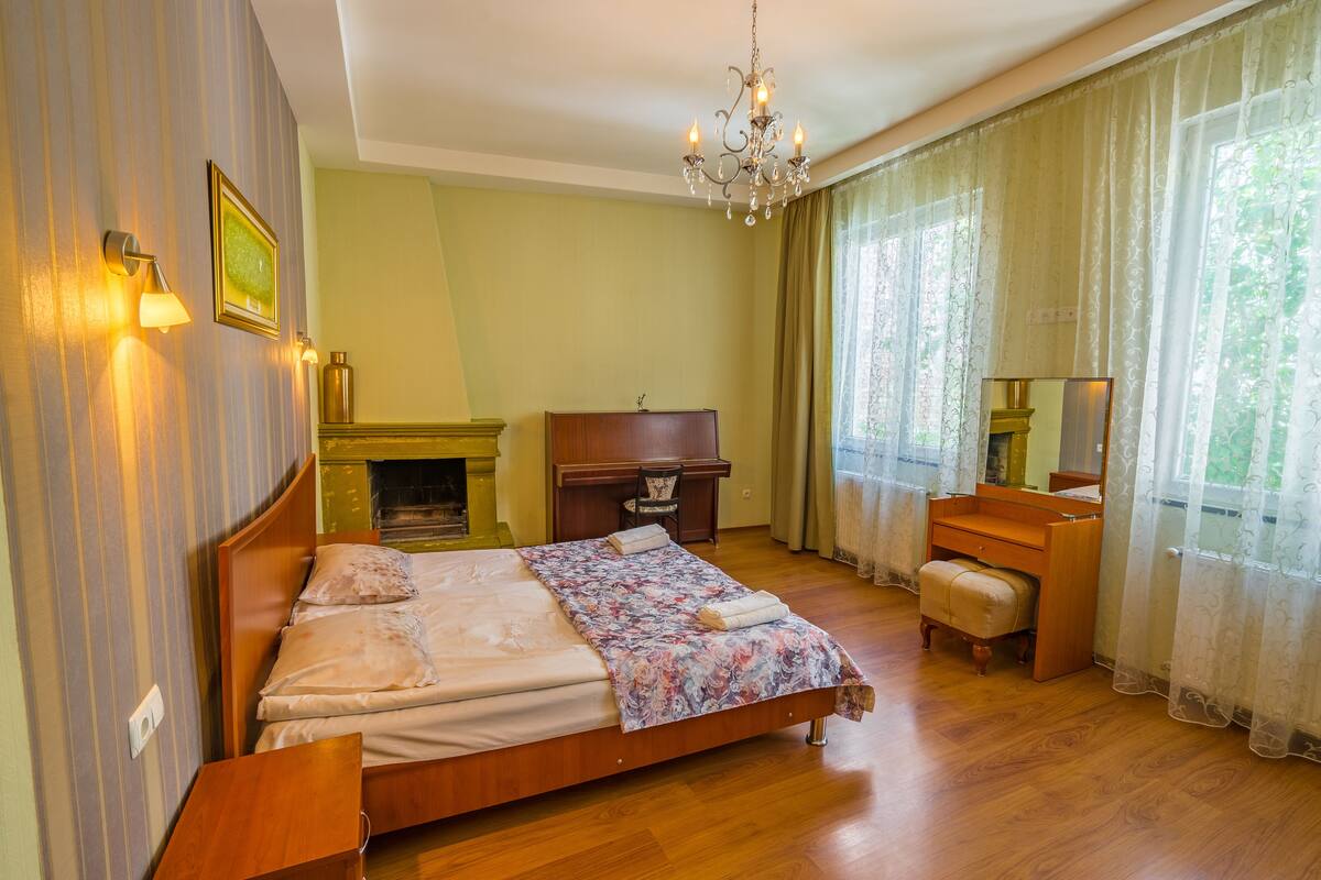 Un dormitorio con cama de madera, cómoda, espejo, escritorio y chimenea.