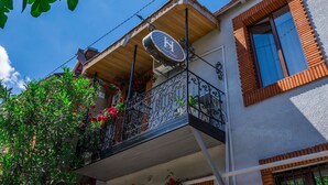 Un hotel con balcón, un letrero con un logotipo y una ventana con marco de ladrillo.