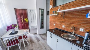 Una cocina compacta con salpicadero de ladrillo, armarios blancos y un lavamanos.