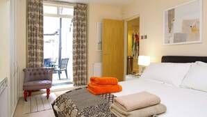A hotel room with a bed, a chair, a table, and a view of the outside. - The London Agent Chelsea Finborough (London)