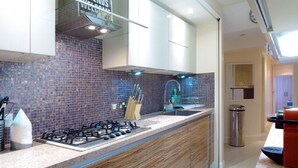 A modern kitchen with a gas stove, wooden cabinets, and a tiled backsplash. - The London Agent Chelsea Finborough (London)