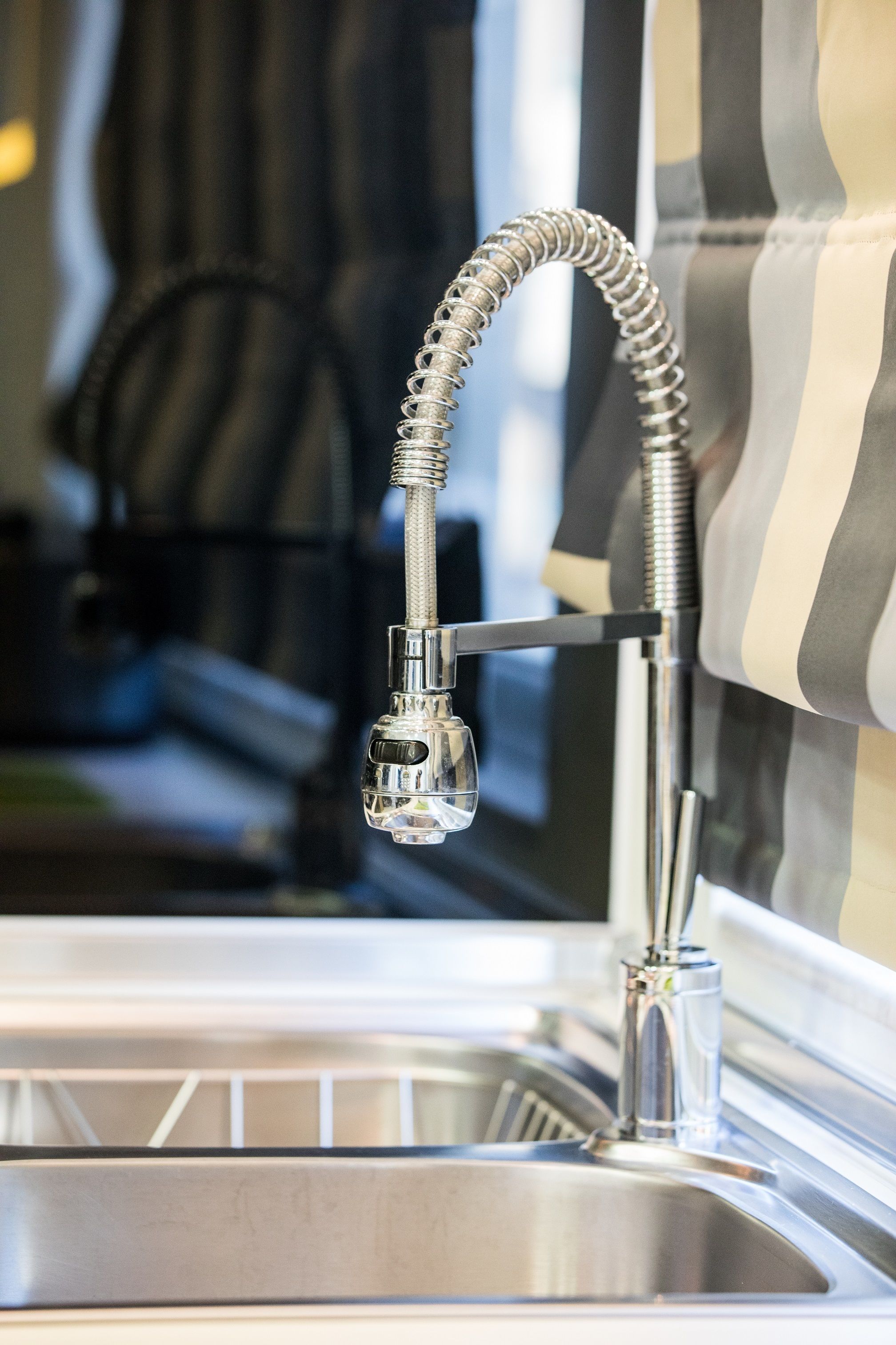 A modern kitchen with a stainless steel sink and a flexible faucet.