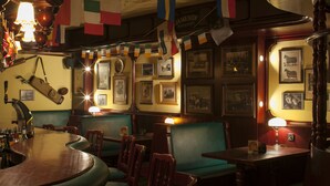 A bar area with wooden furniture, green cushioned booths, and various flags. - Hotel Drei Morgen (Leinfelden-Echterdingen)