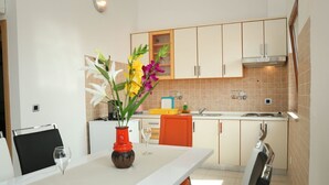 Eine moderne Küche mit weißen Schränken, einem Esstisch mit Stühlen und einer Vase mit Blumen.