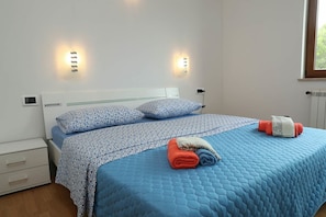 Une chambre à coucher avec un lit, deux lampes fixées au mur, une fenêtre et un radiateur.