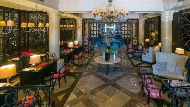 Eine großzügige Lobby mit einer Kandelaber, Sitzbereichen und einer Rezeption.