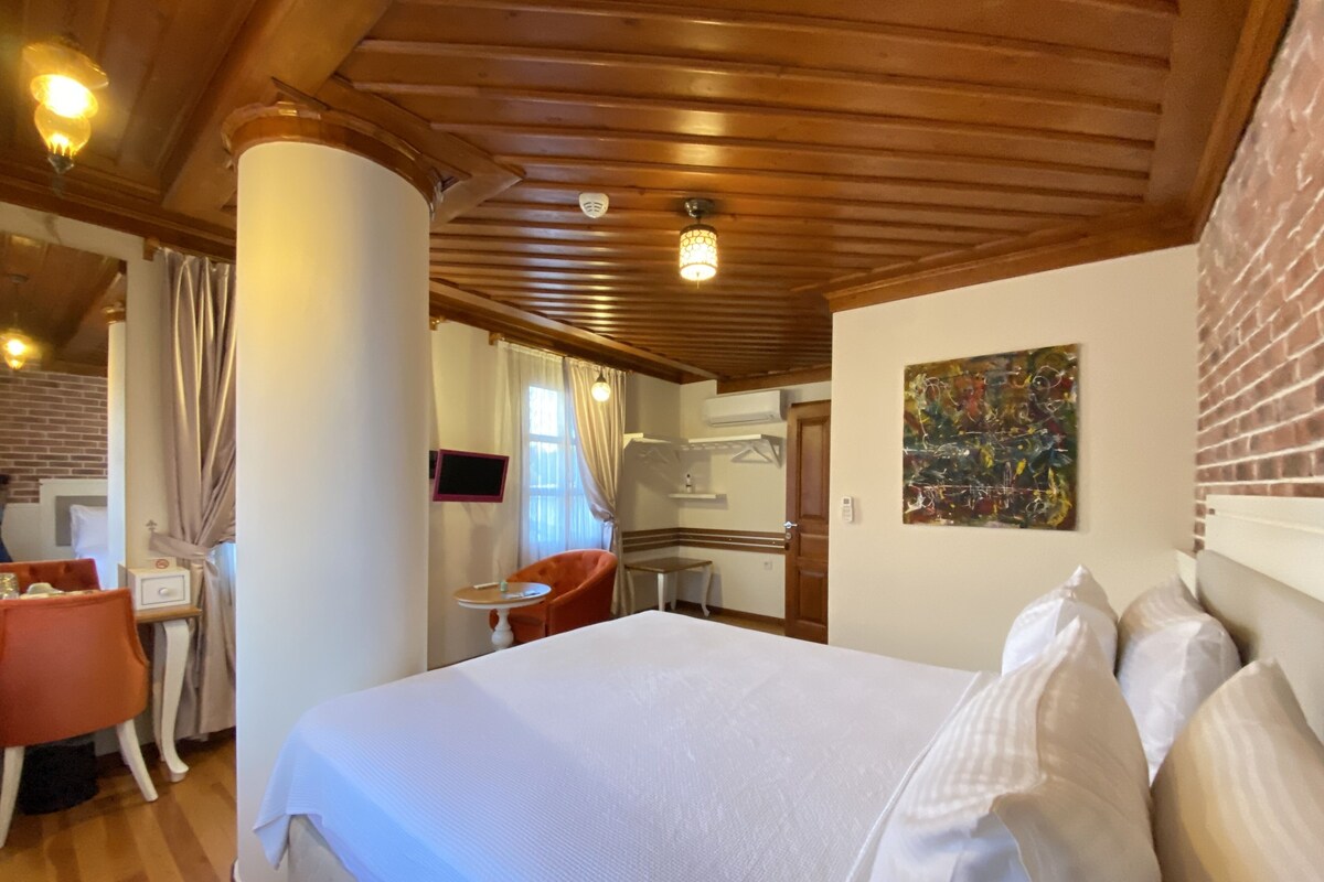 A hotel room with a large bed, a desk, a chair, and a small table.