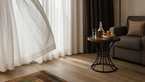A modern living room with a sofa, a round table with a lamp, and sheer curtains. - Sparkle Hotel (Istanbul)