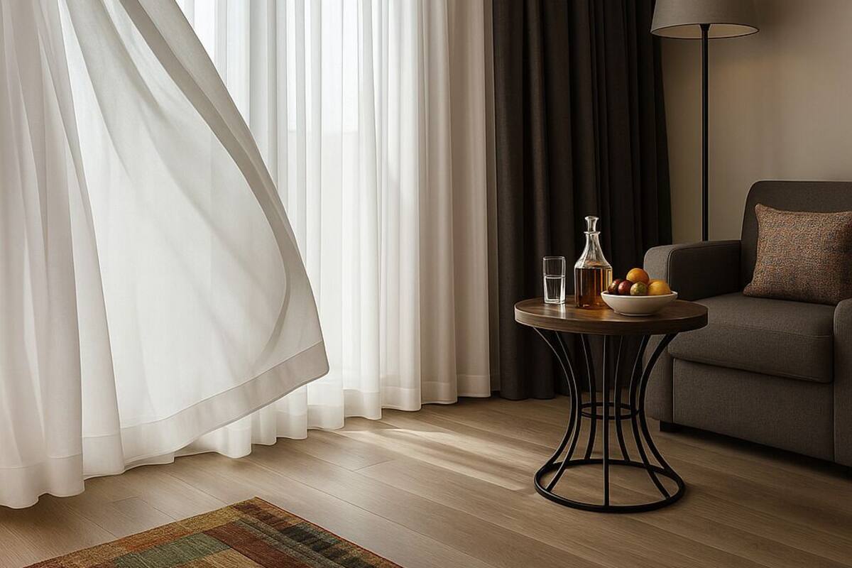 Una sala de estar moderna con un sofá, una mesa redonda con una lámpara y cortinas de gasa.