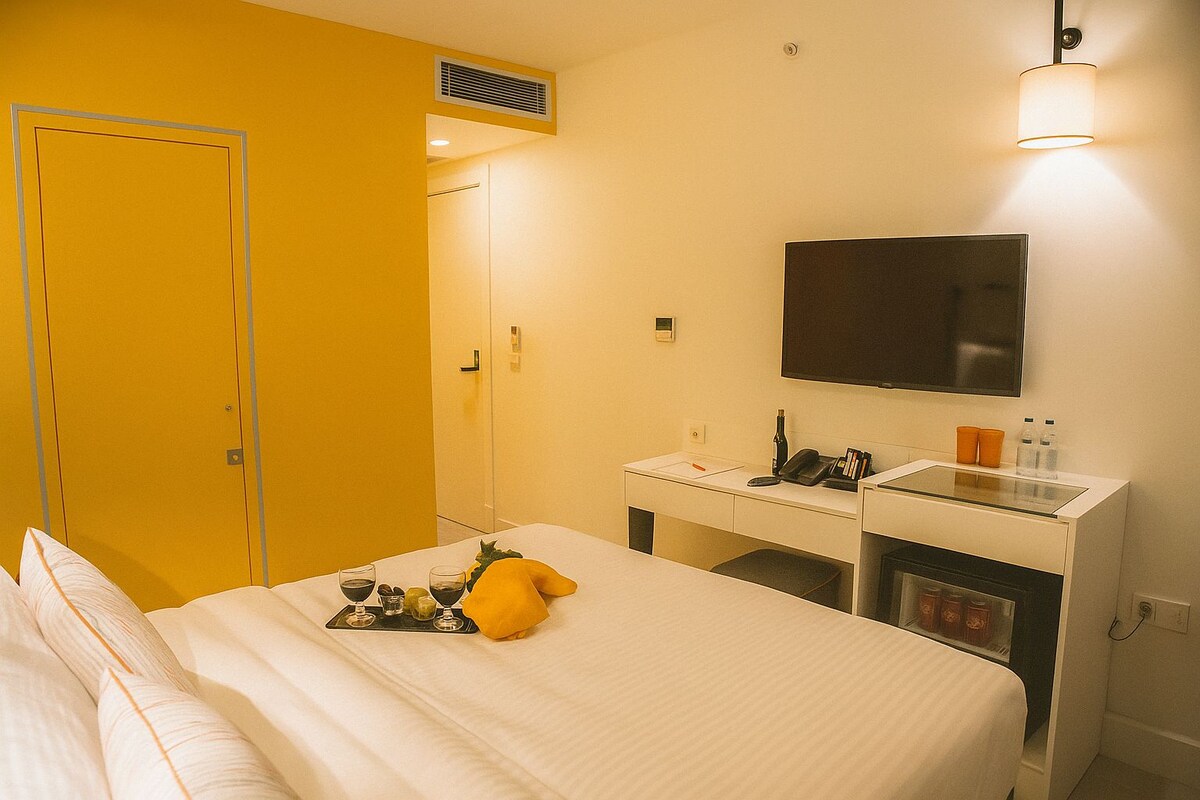 A hotel room with a bed, a desk, a television, and a minibar.