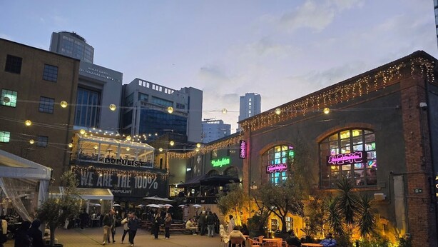 An urban square with outdoor seating, a café, and a building with illuminated signage. - Sparkle Hotel (Istanbul)