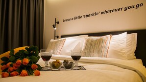 A neatly made bed with white linens, two glasses of red wine, and a bouquet of orange roses on a tray. - Sparkle Hotel (Istanbul)