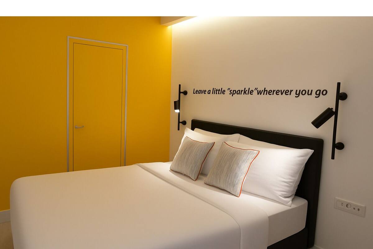 Una habitación de hotel con cama, una lámpara de pared y una frase motivacional.