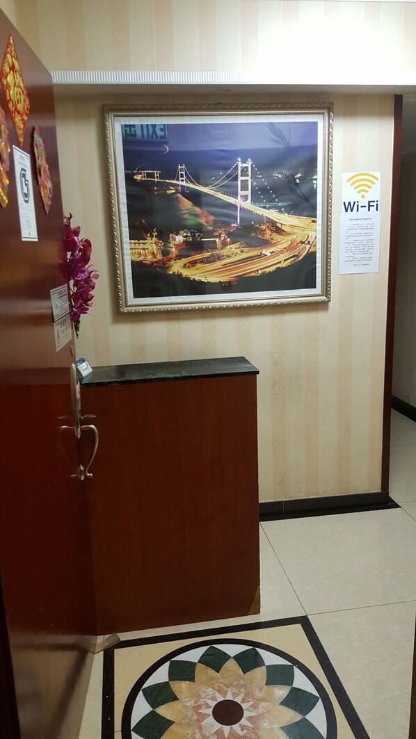 A reception desk with a framed picture of a bridge, a Wi-Fi sign, and a decorative flower. - Jin Xiang Hotel (Kowloon)