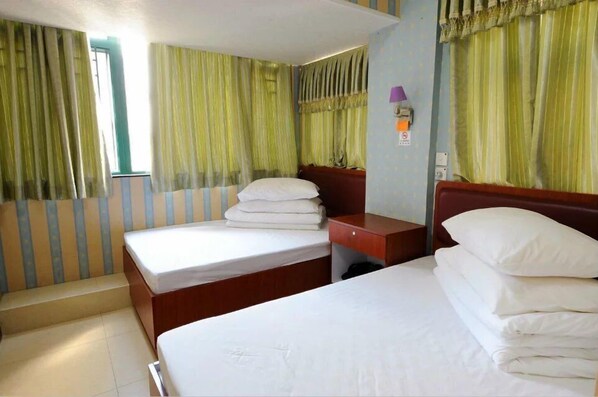 A hotel room with two beds, a wooden nightstand, and green striped curtains. - Jin Xiang Hotel (Kowloon)