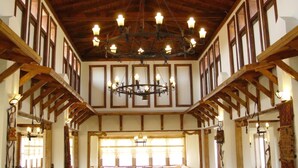 Quarto com teto de madeira alto, grandes janelas e um lustre.