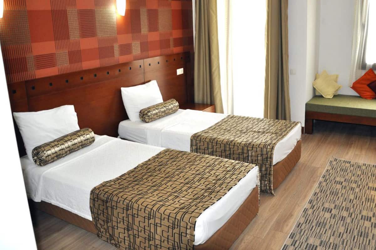 Een hotelkamer met twee bedden, een bankje en een kamerkleed met dessin.