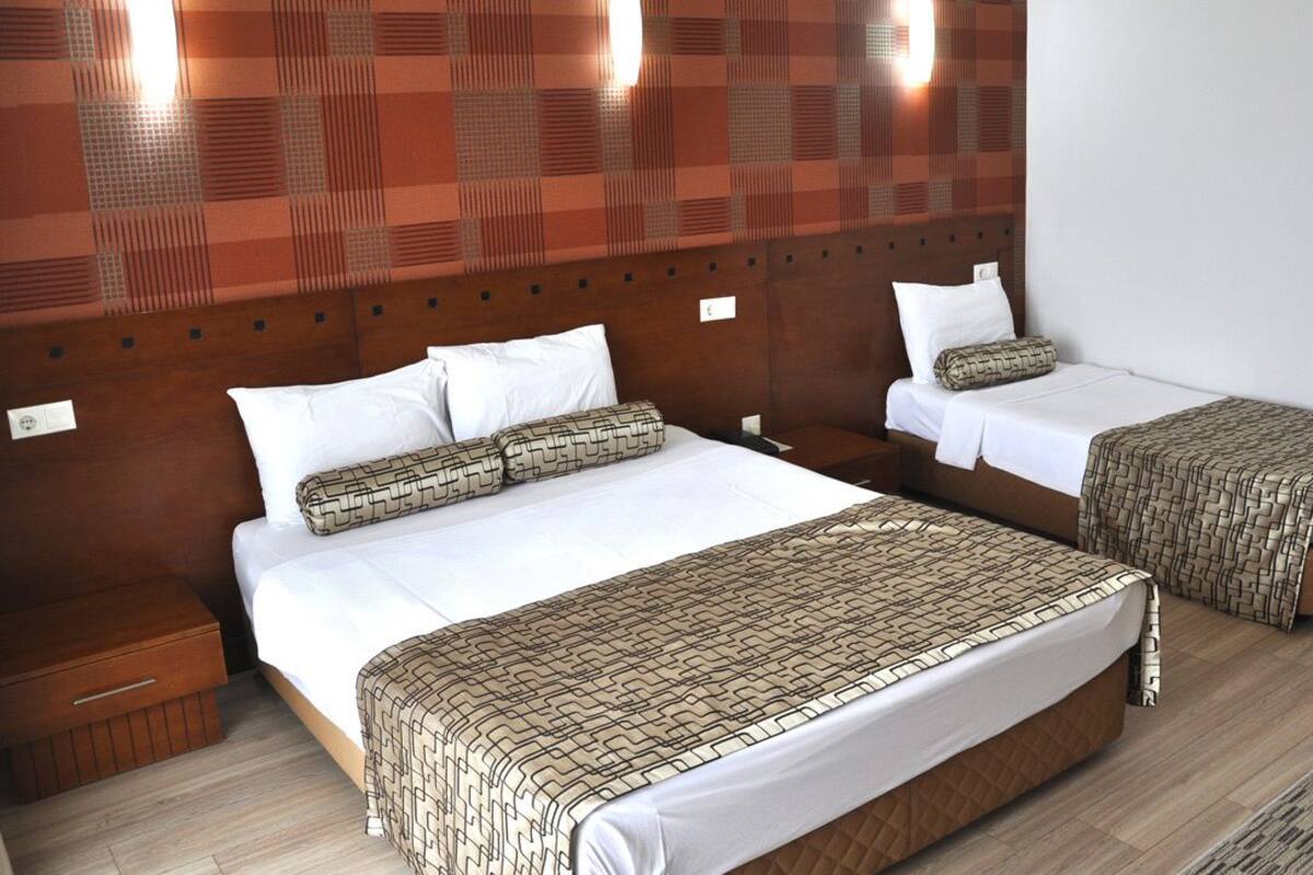 Een hotelkamer met twee bedden, elk voorzien van een beddeken met een patroon, een houten hoofdbord en nachtkastjes.