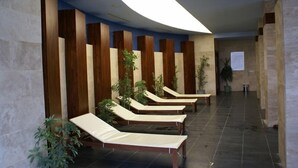 Uma área de spa com vários espreguiçadeiras dispostas contra uma parede com painéis de madeira vertical.