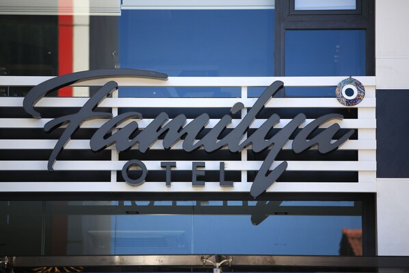 Une enseigne d’hôtel portant le nom « Familya Hotel », écrit dans une typographie stylisée.