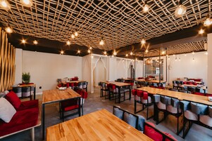 A modern restaurant with wooden tables and chairs, a unique woven ceiling, and ambient lighting.