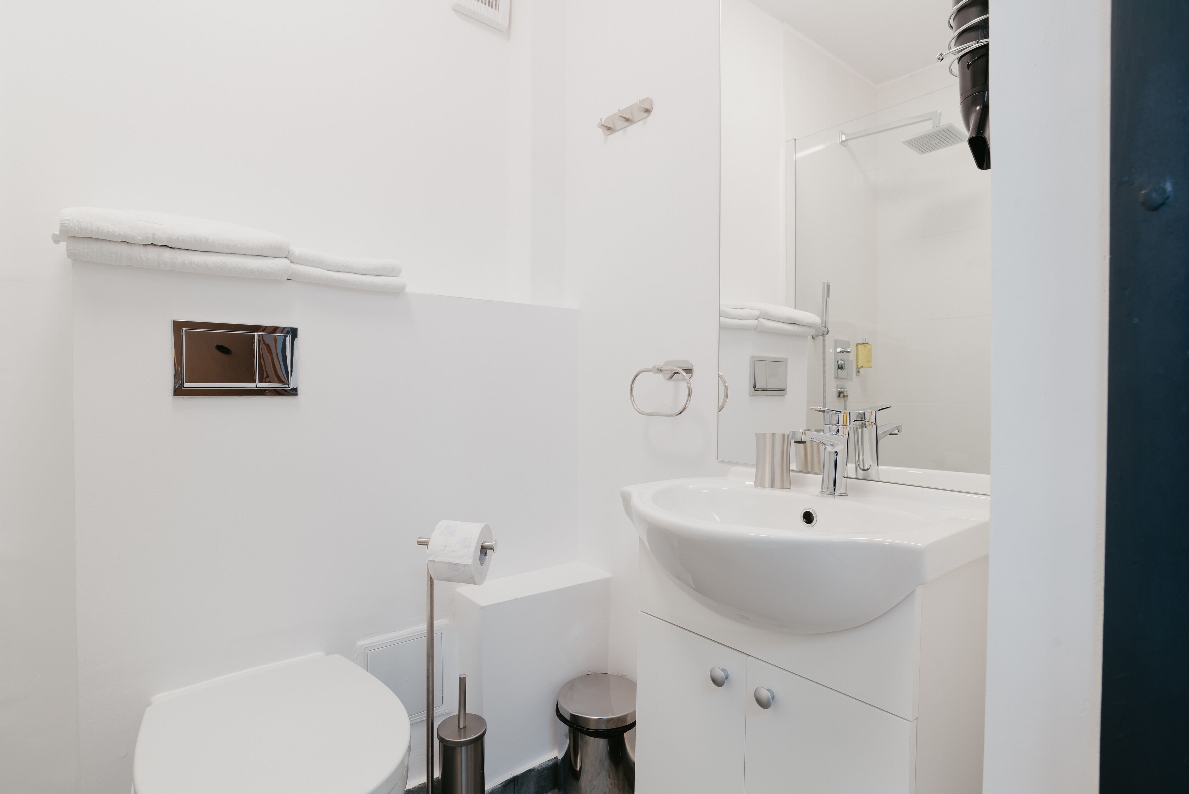 A modern bathroom with a white sink, mirror, and toilet.