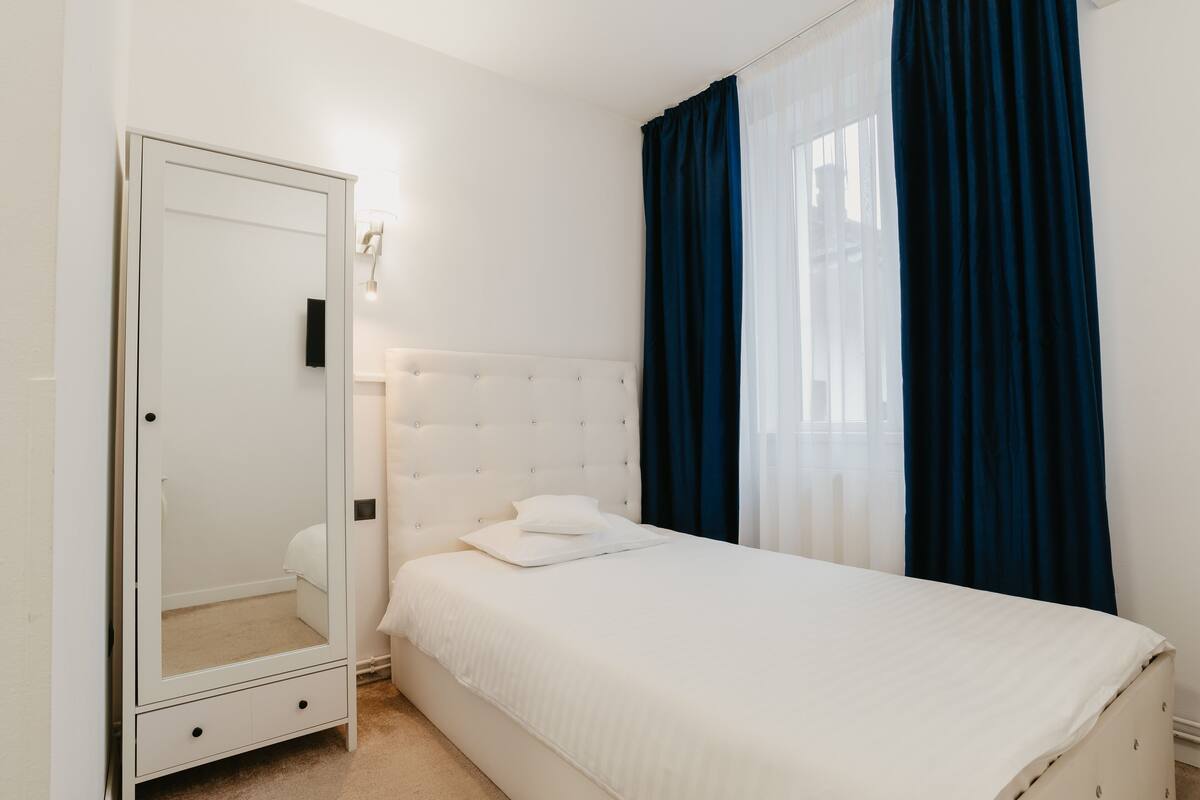 A bedroom with a bed, a wardrobe, and a mirror.