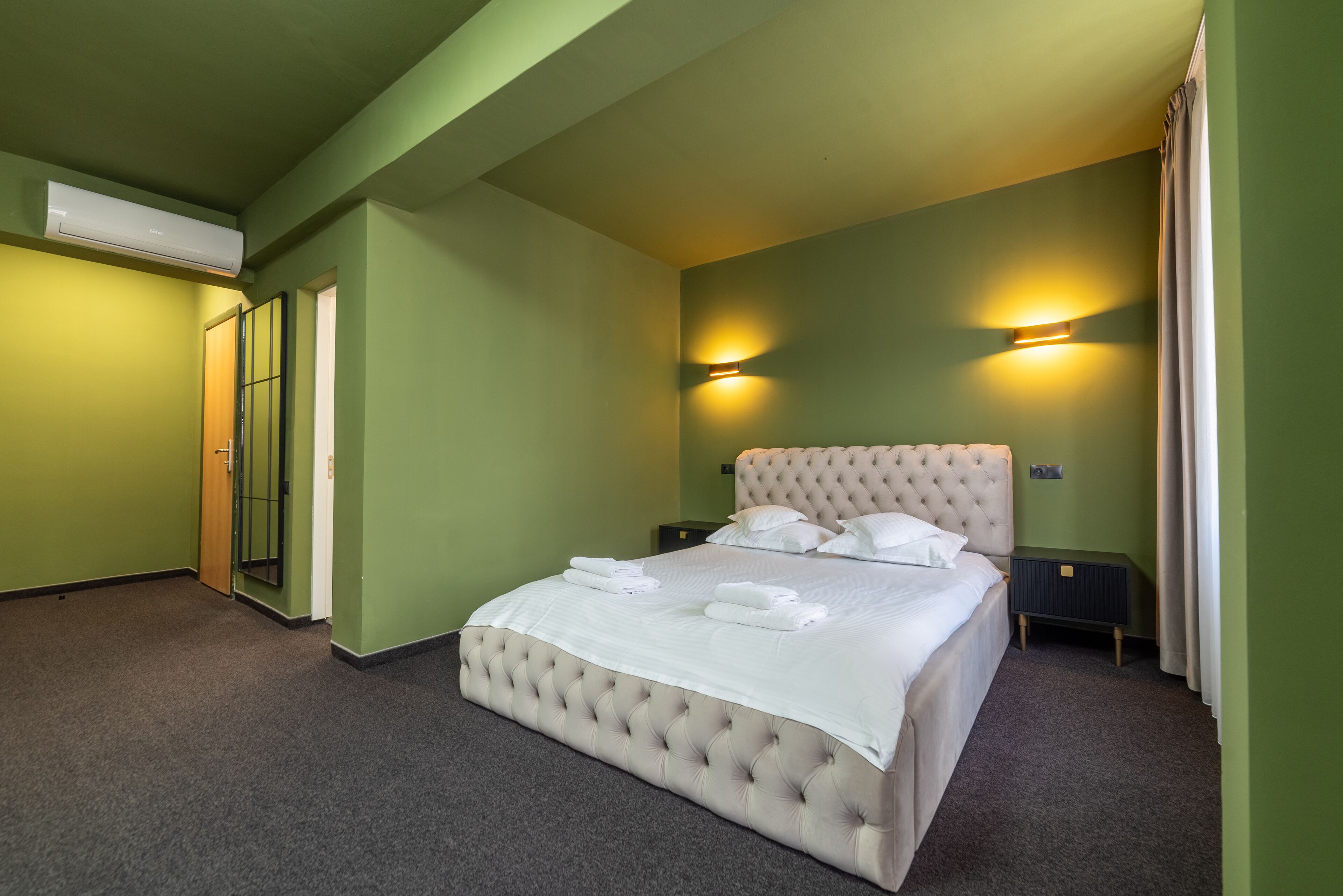 A neatly made bed with white linens and towels, a tufted headboard, and two bedside lamps.