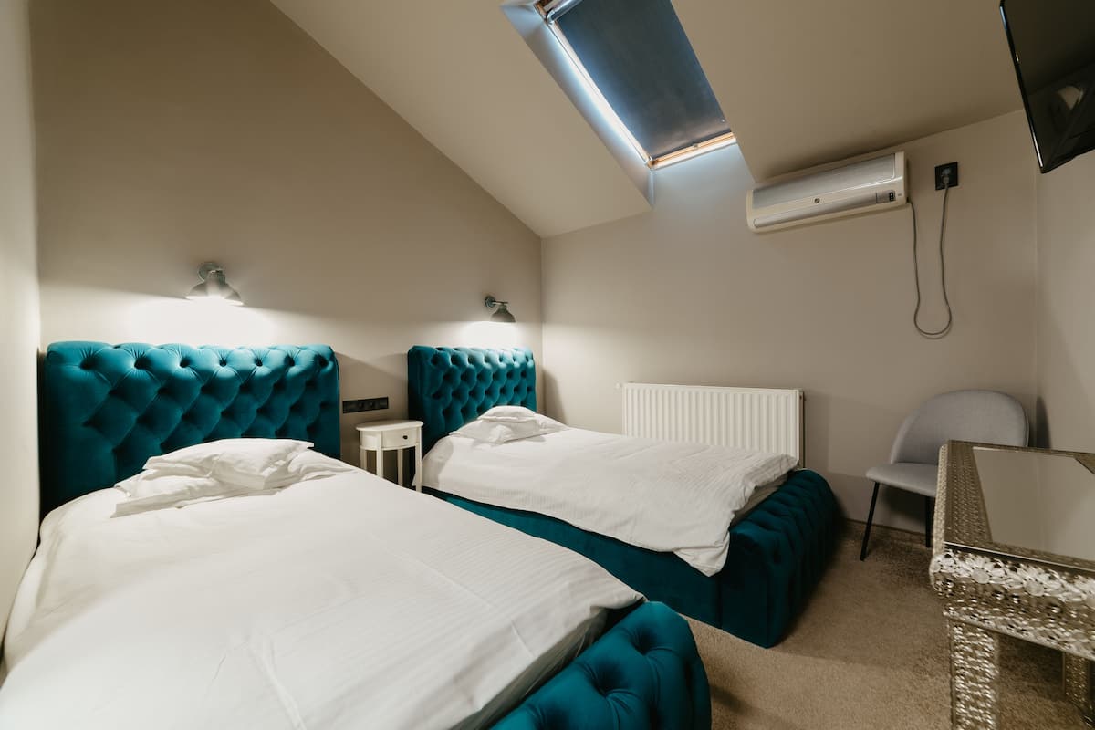A hotel room with two beds, a desk, a chair, and a TV.