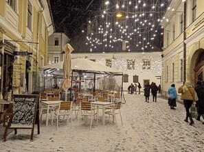 Un café al aire libre con mesas y sillas, rodeado de edificios.