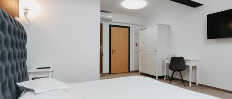 Une chambre d’hôtel équipée d’un lit, d’un bureau, d’une armoire et d’un téléviseur.