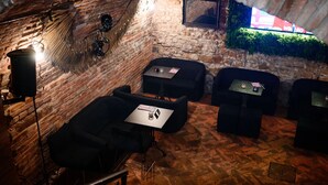 A cozy, dimly lit room with brick walls, a small table with a card, and a chair. - Fullton Central Inn (Cluj-Napoca)