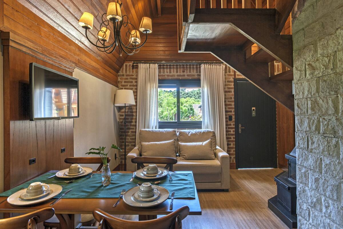A cozy dining area with a wooden table set for two, a sofa, and a fireplace.