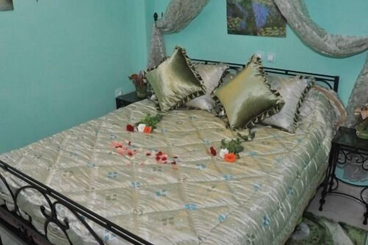 A bed with a floral bedspread, multiple pillows, and a nightstand with a lamp.