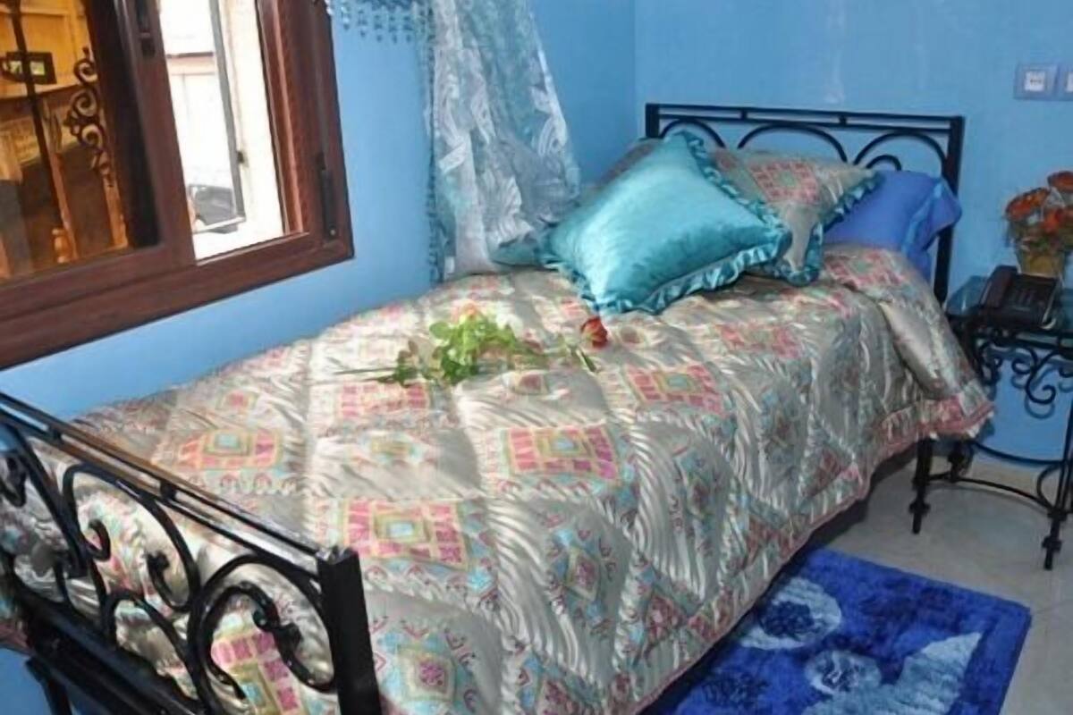 A bedroom with a bed, a window, and a nightstand.